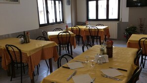 Un espace repas avec des tables dressées pour les repas, des chaises et une horloge au mur.