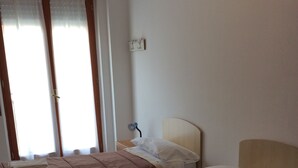 Une chambre d’hôtel avec deux lits, une table de chevet, une lampe et une fenêtre avec des rideaux.
