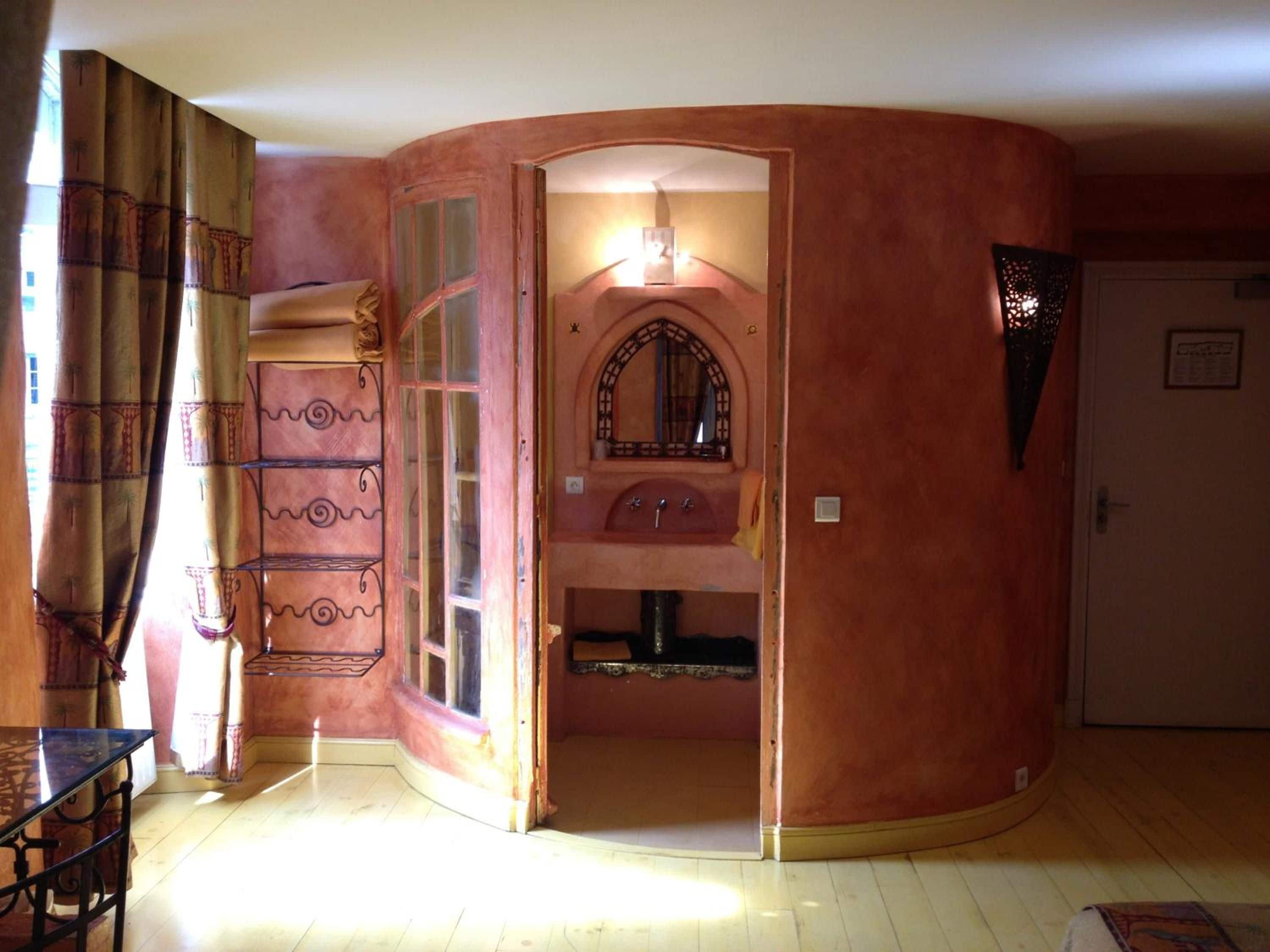 A room with a curved wall, a built-in sink, and a mirror above it.