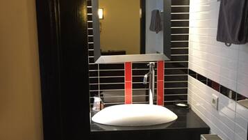 Un baño con un lavamanos blanco, un espejo y detalles rojos en la pared.