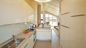 Una cocina moderna con gabinetes blancos, electrodomésticos de acero inoxidable y una isla central.