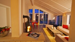 Una sala de estar moderna con una chimenea de leña, un televisor y una zona de estar acogedora.