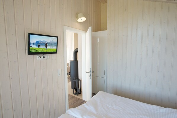 A room with a bed, a TV mounted on the wall, and a door leading to another room.