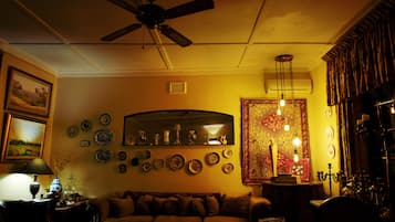 A cozy living room with a ceiling fan, a sofa, and a wall adorned with various decorative plates and a tapestry.