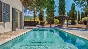 A rectangular swimming pool with clear water, surrounded by a stone deck. There are two lounge chairs and a sun umbrella. - Cozy home in St Florent (St Florent)