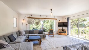 Un salon spacieux avec un canapé d’angle, une petite table et un téléviseur.