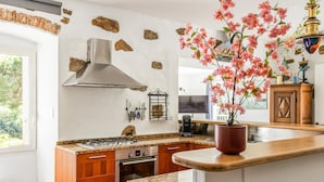 Une cuisine équipée d’une cuisinière à gaz, d’un four et agrémentée d’un vase décoratif contenant des fleurs roses.