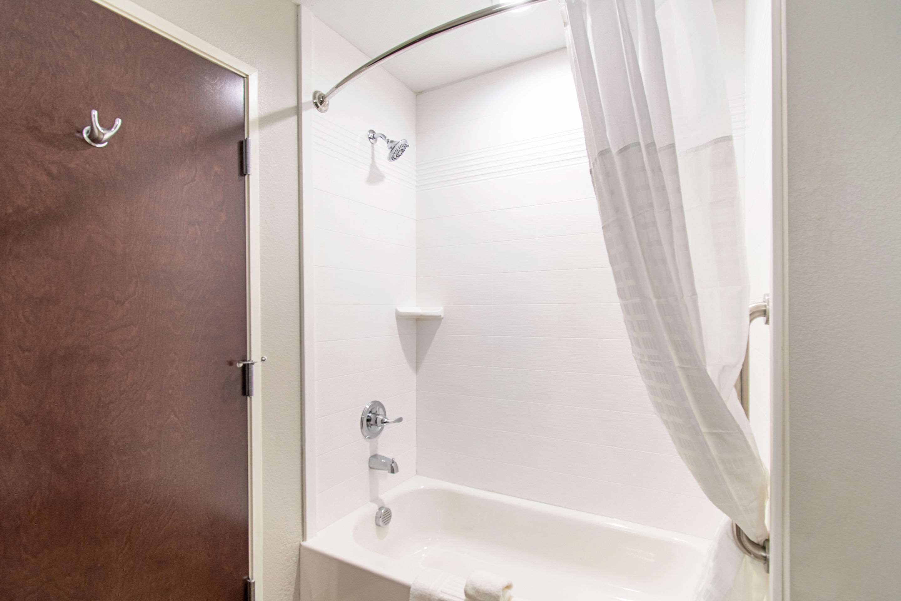 Un baño con bañera, ducha y puerta de madera.