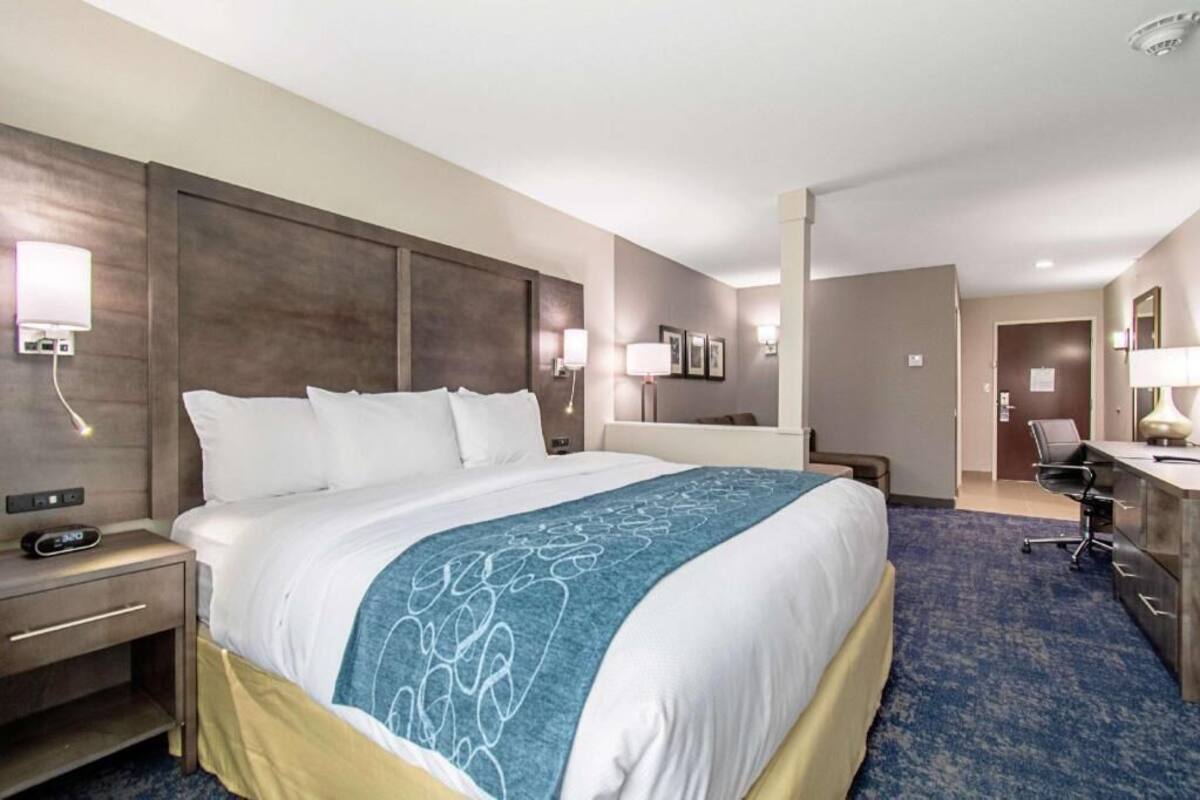Une chambre d’hôtel avec un grand lit, des tables de chevet, un bureau et une chaise.