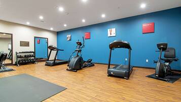 A gym with treadmills, elliptical machines, and a rack of dumbbells.