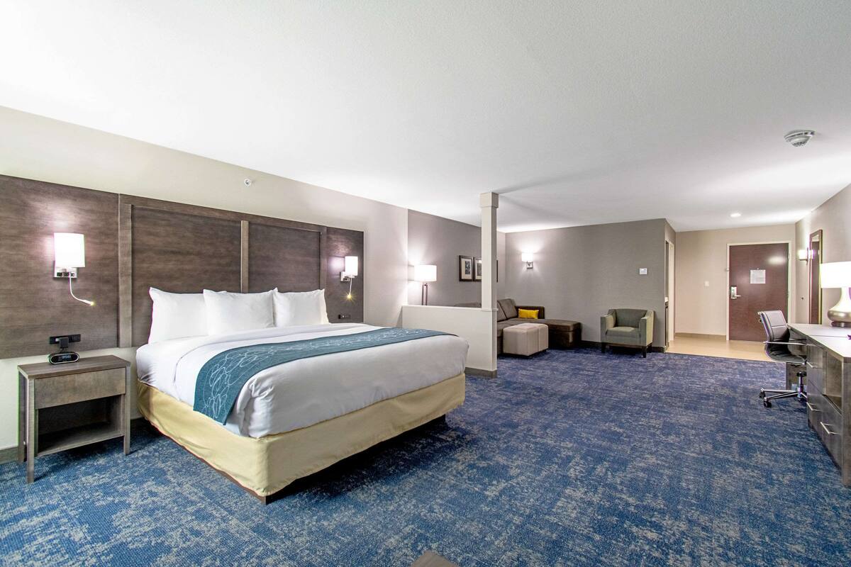 Een hotelkamer met een groot bed, nachtkastjes, een bureau en een stoel.