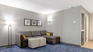 Una sala de estar con un sofá modular, un reposapiés y luminarias fijadas a la pared.