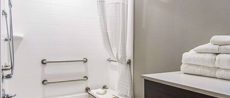 Un baño con una bañera blanca, un perchero y una pila de toallas sobre un mostrador.