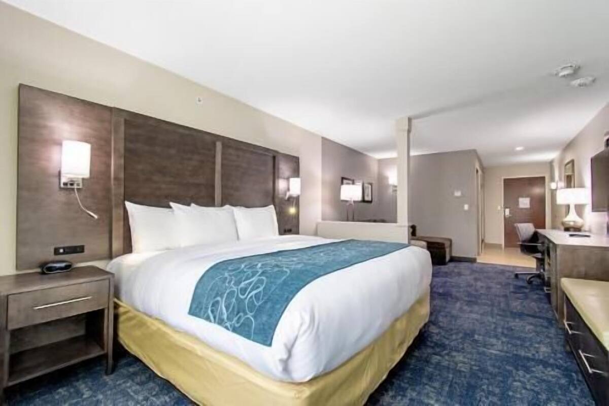 Een hotelkamer met een groot bed, nachtkastjes, een bureau en een stoel.