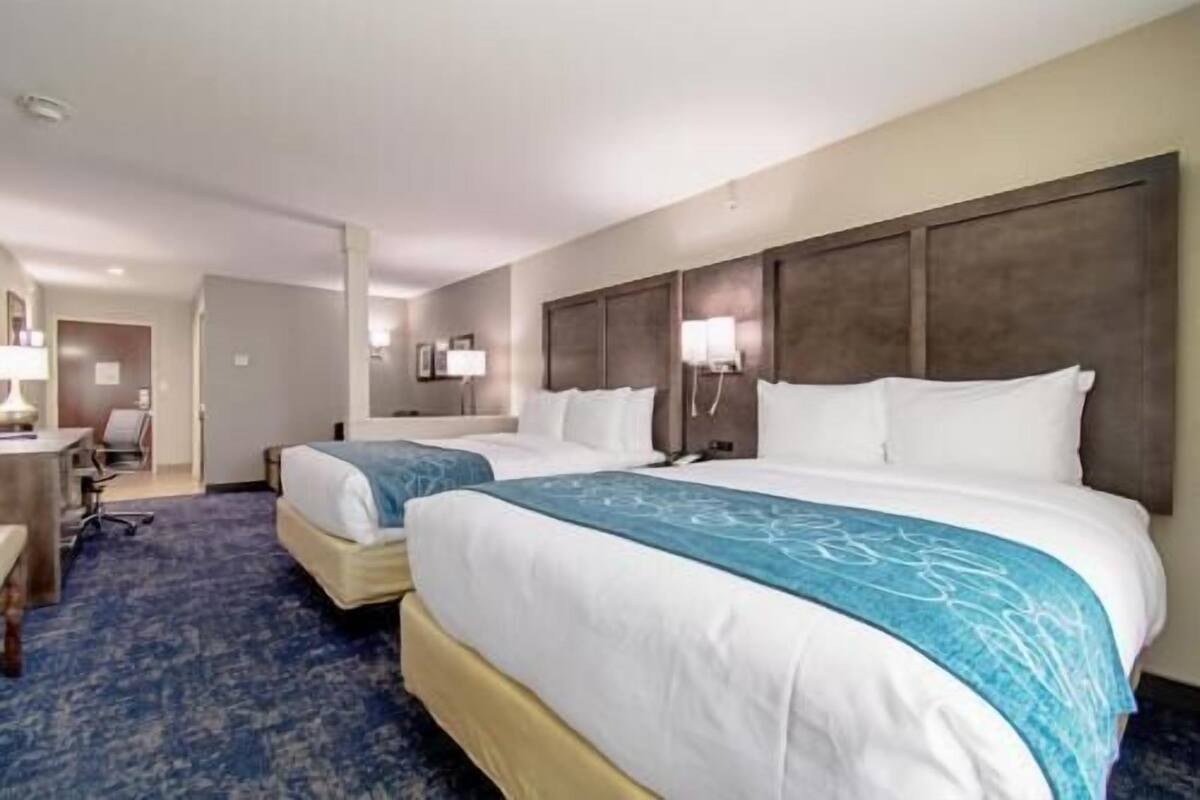Een hotelkamer met twee bedden, een bureau, een stoel en een lamp.