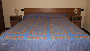 A neatly made bed with a floral quilt, two bedside tables with lamps, and a wooden headboard. - B&B Milano Malpensa 1 (Castano Primo)