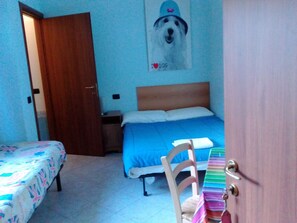 A bedroom with a bed, a chair, a desk, and a poster on the wall.