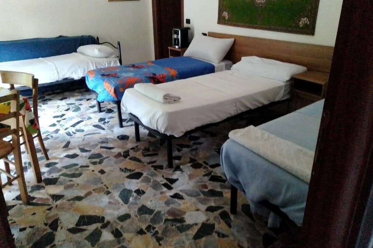 Ein Hotelzimmer mit drei Betten, einem kleinen Tisch und einem Stuhl.
