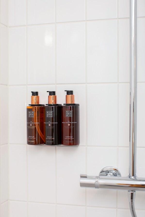 A bathroom with three bottles of Ritual of Happy Buddha products on a tiled wall. - Clarion Hotel Oslo (Oslo)
