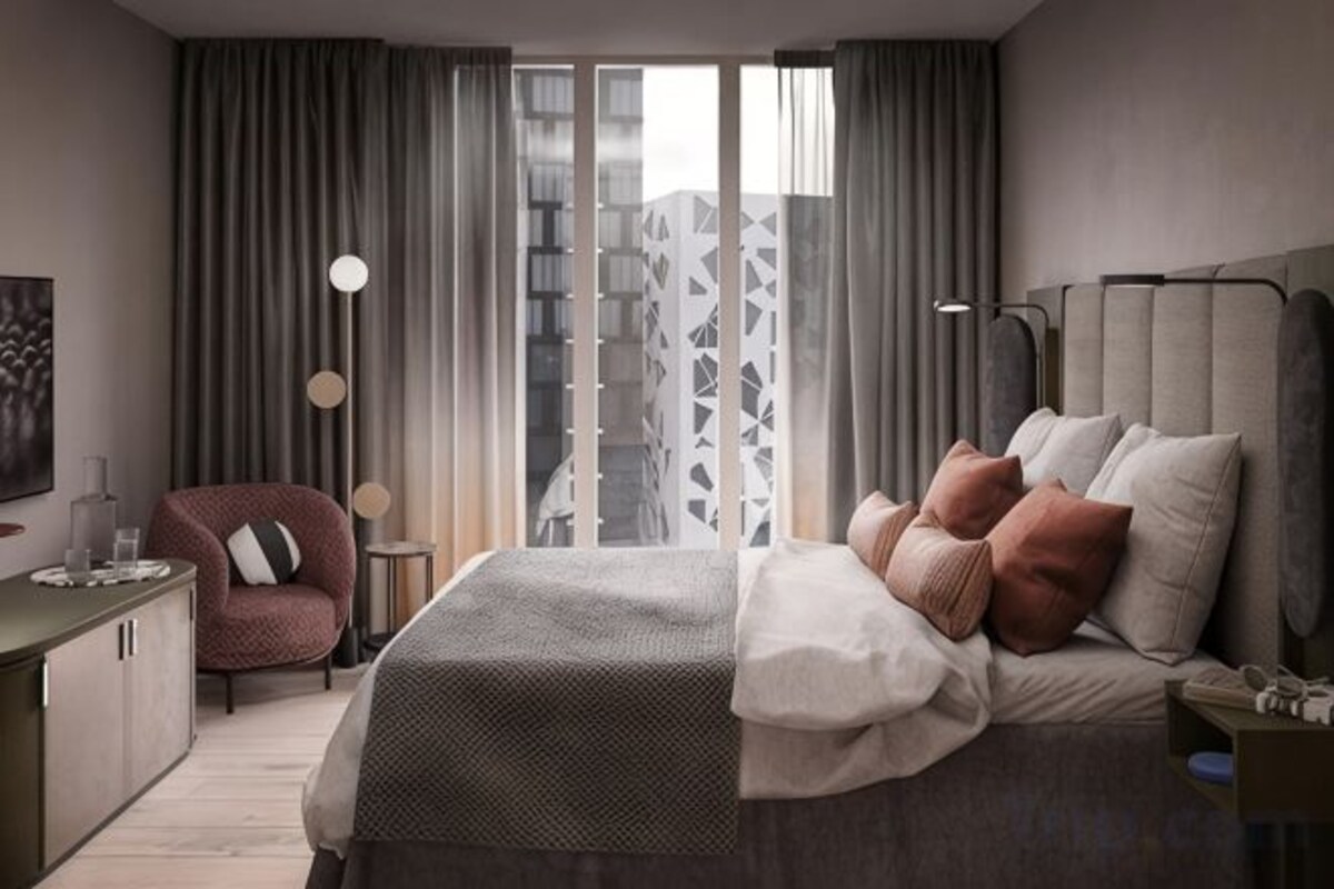 Habitación de hotel moderna con una cama grande, un escritorio, una silla y vistas a la ciudad a través de amplios ventanales.