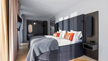 A modern bedroom with a large bed, bedside tables, a desk, and a chair.