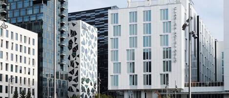 Un hotel moderno con fachada geométrica, varios pisos y una entrada destacada.