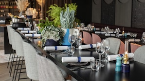 A dining area with a long table set for a meal, featuring neatly arranged plates, cutlery, and glasses. - Clarion Hotel Oslo (Oslo)