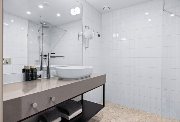 Un baño moderno con un espejo grande, un lavabo blanco y un mueble de tocador negro.