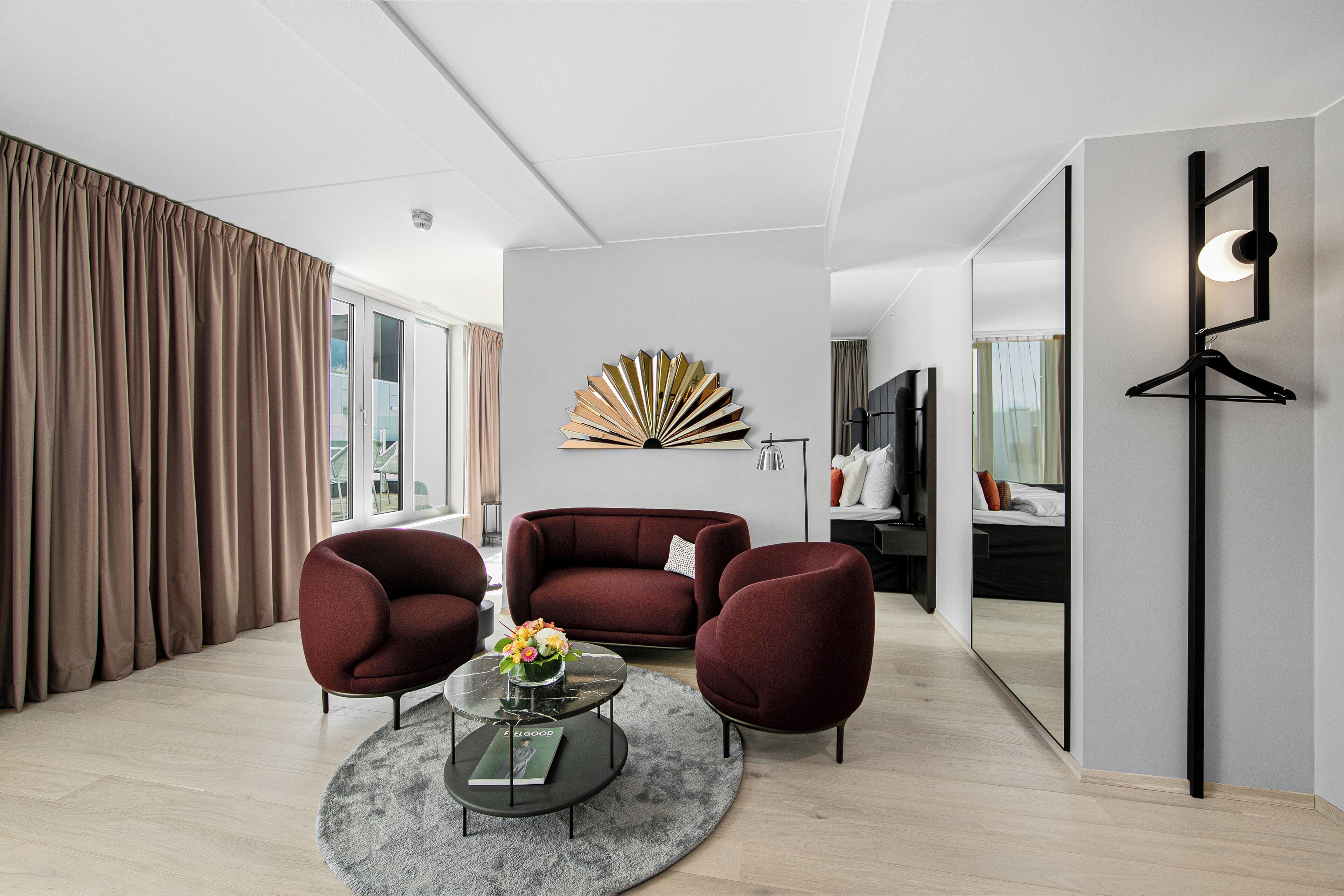 A modern living room with a sofa, two armchairs, a coffee table, and a decorative wall piece.