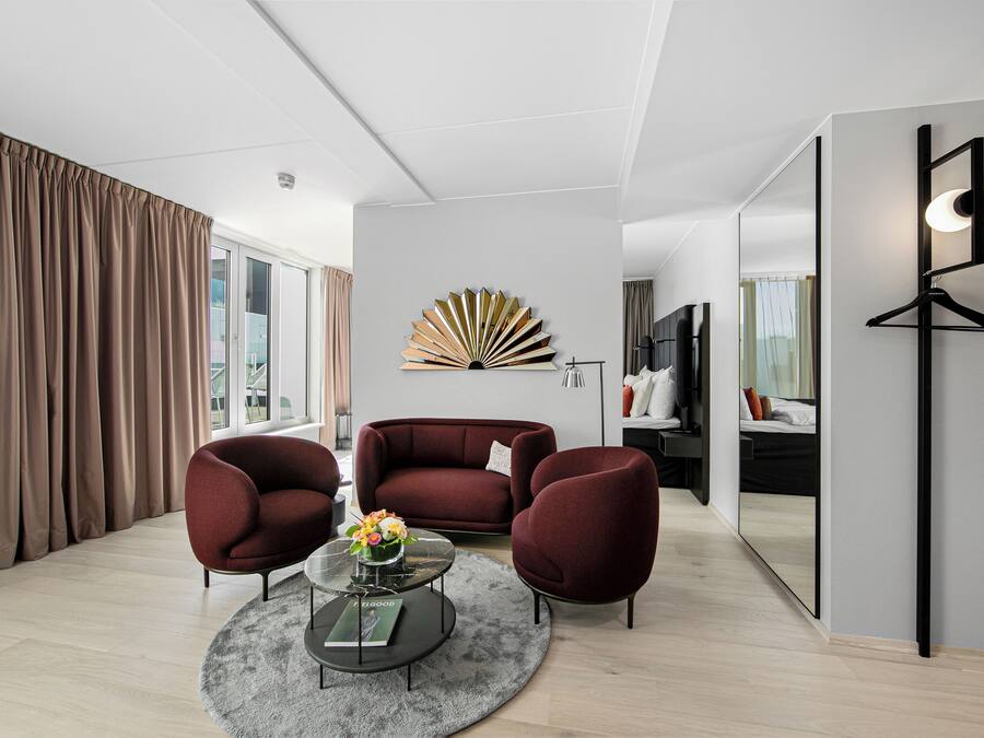 A modern living room with a sofa, two armchairs, a coffee table, and a decorative wall piece.