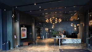 A modern lobby with a marble floor, a reception desk, a large painting on the wall, and a unique chandelier. - Clarion Hotel Oslo (Oslo)