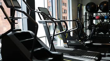 Una palestra con tapis roulant, una rastrelliera per pesi e palle da ginnastica.