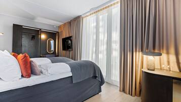 Quarto moderno com uma cama grande, uma TV e uma mesa de cabeceira com luminária.