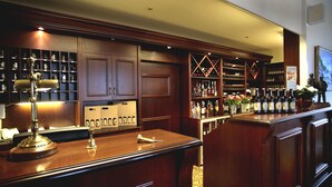 A bar area with wooden cabinets, a bar counter, and shelves stocked with bottles. - Tornøes Hotel (Kerteminde)