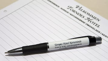Un bolígrafo sobre papel rayado con texto en un idioma extranjero, probablemente una nota de bienvenida de un hotel.