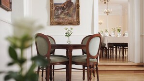A dining area with a wooden table and chairs, a painting on the wall, and a vase with flowers. - Tornøes Hotel (Kerteminde)