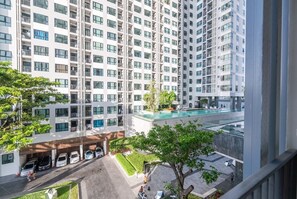 A high-rise residential building with multiple balconies, a rooftop pool, and a parking area.
