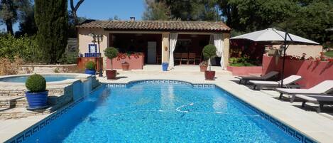 Una piscina al aire libre, sombrillas, sillones reclinables de piscina