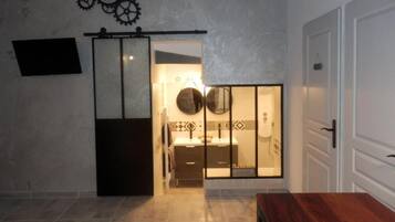 A modern bathroom with a large mirror, a clock, and a wooden bench.