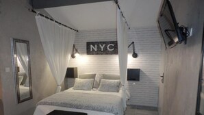 A bedroom with a canopy bed, a mirror, a wall-mounted TV, and a sign reading "NYC". - Mas Les Vieux Chenes (Lambesc)