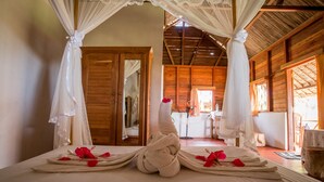 Una habitación con una cama decorada con toallas y pétalos de rosa, paredes de madera y un ventilador de techo.