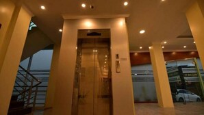An interior view of a hotel lobby with a glass elevator, a staircase, and a car dealership sign in the background. - Hotel Grace Taunggyi (Taunggyi)