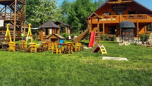 A rustic wooden cabin with a red slide and a wooden play structure. - Bungalows Drevna (Novi Sad)
