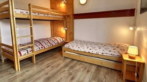 Ein Schlafraum mit Etagenbetten, einer Holzleiter, einem Nachttisch mit Lampe und einer Wandleuchte.