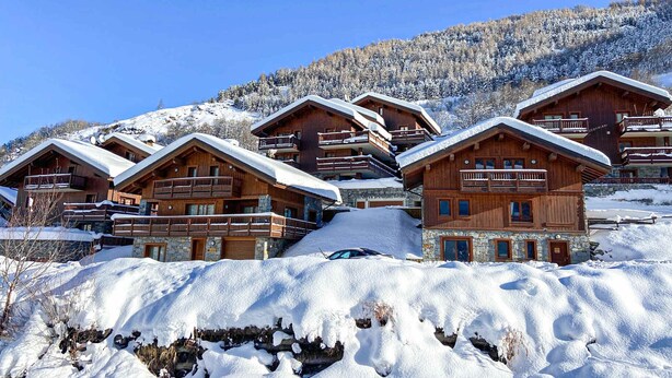 A cluster of wooden cabins with balconies, set against a snowy mountain backdrop. - Spacious 4-Room Apartment with Ski Access, Balcony, and Stunning Views near Les Menuires (Saint-Martin-de-Belleville-Les Menuires)