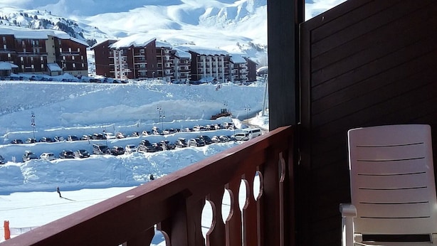 A balcony with a view of a snow-covered mountain and a parking lot. - South-facing apartment at slopes, 5 people, balcony (Plagne Soleil)
