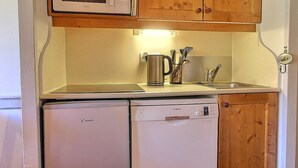 A compact kitchen with a microwave, a Bosch dishwasher, wooden cabinets, and a stainless steel coffee pot. - South-facing apartment at slopes, 5 people, balcony (Plagne Soleil)