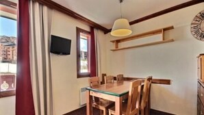 Ein Essbereich mit Holztisch und -stühlen, einem an der Wand befestigten Fernseher und einer Wanduhr.