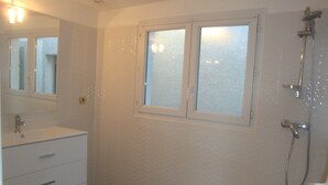 Un baño con lavamanos, espejo y ducha blancos.