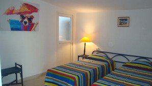 Una habitación con dos camas, una silla, una lámpara y un cuadro en la pared.